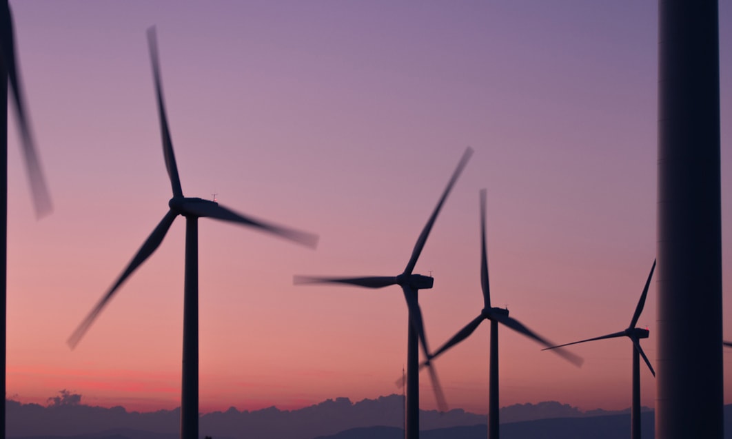 a group of wind turbines in the sunset