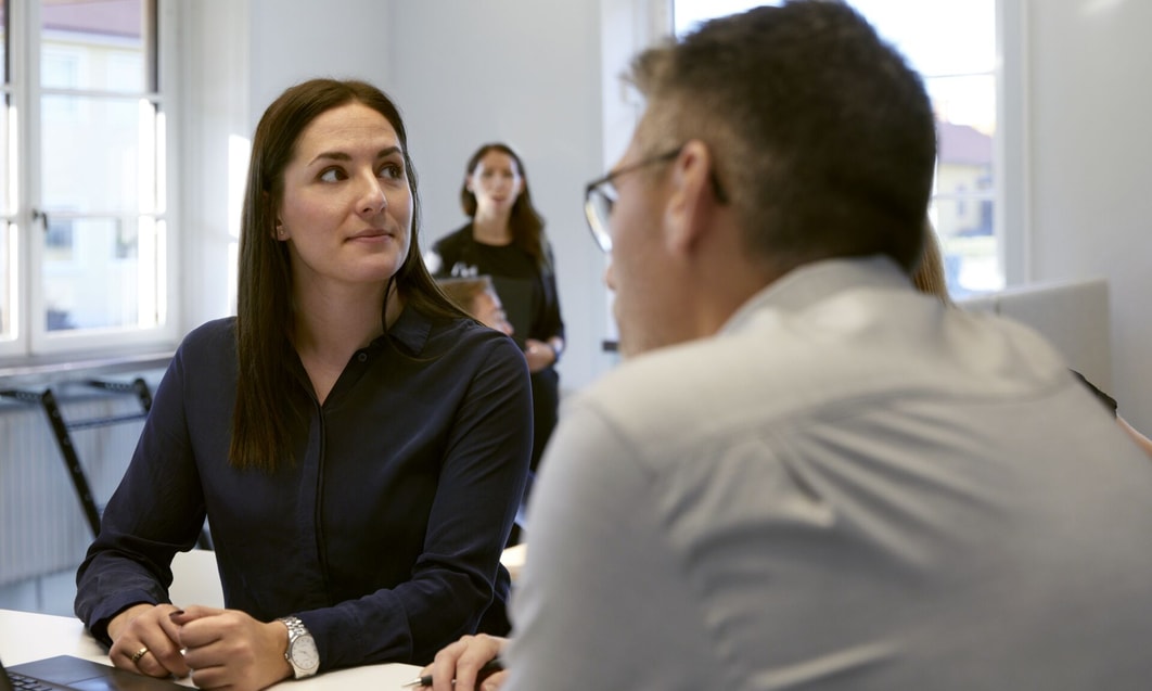 a person sitting at a table with a person in the background