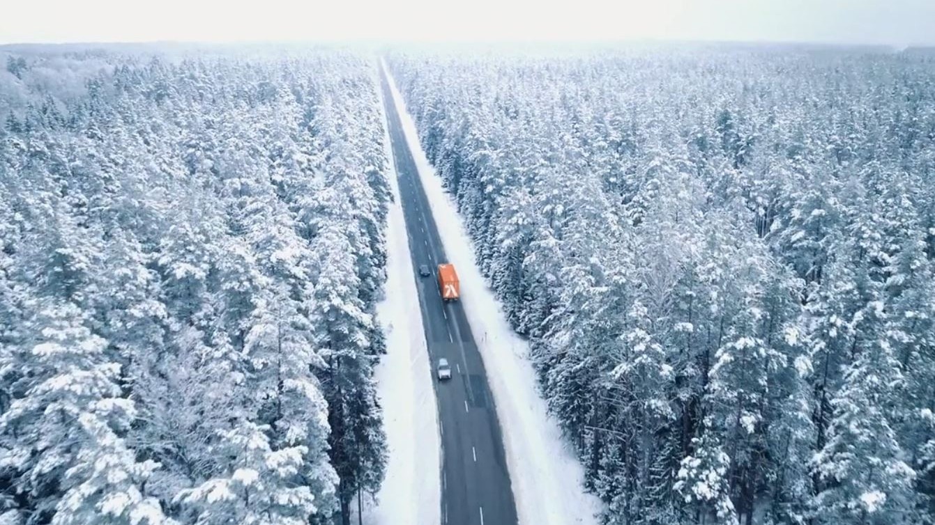 a road with cars on it and trees covered in snow