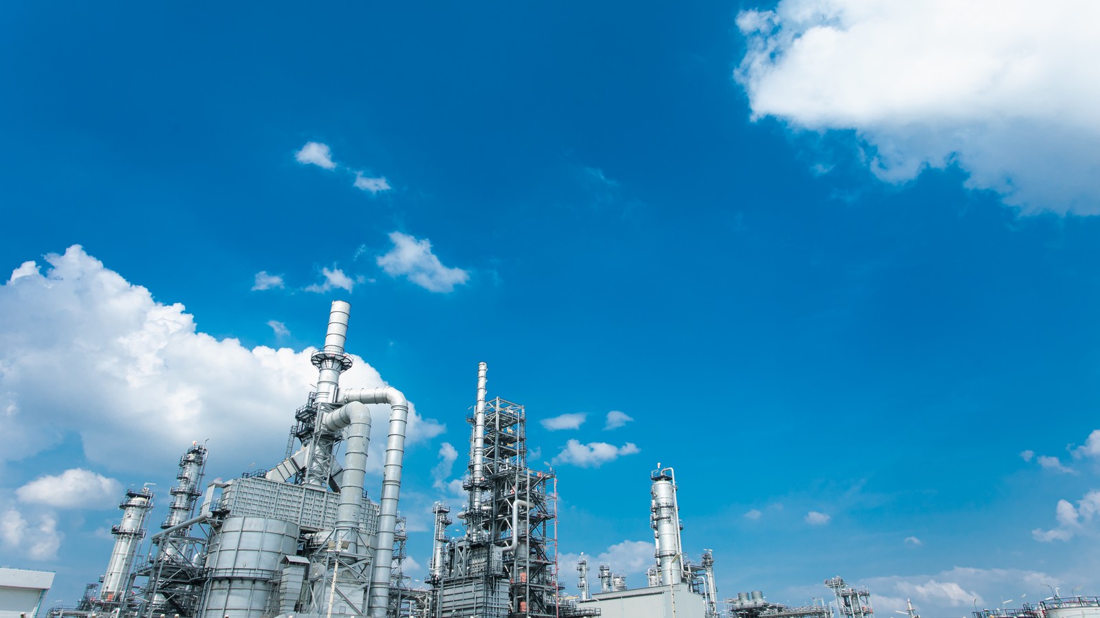 a large factory with blue sky and clouds